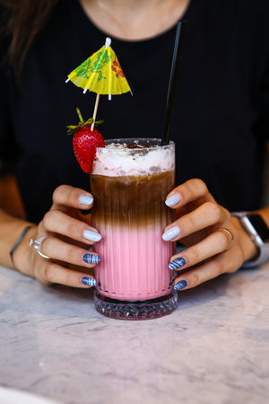 Iced coffee with milk. Iced coffee latte. Woman holding glass cup of iced coffee.