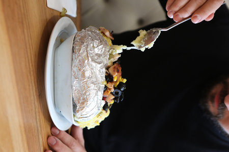Baked kumpir potato stuffed with the cheese, sausage, olives, peppers and corn