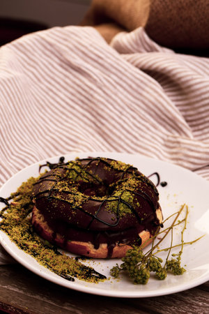 Delicious donut with chocolate sauce and pistachio nut pieces.の写真素材