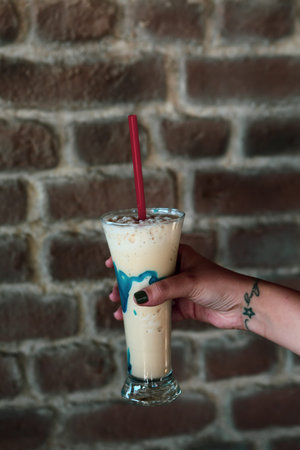 Iced coffee with milk. Iced coffee latte. Woman holding glass cup of iced coffee.