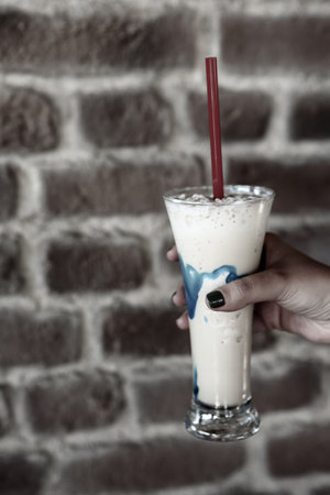 Iced coffee with milk. Iced coffee latte. Woman holding glass cup of iced coffee.