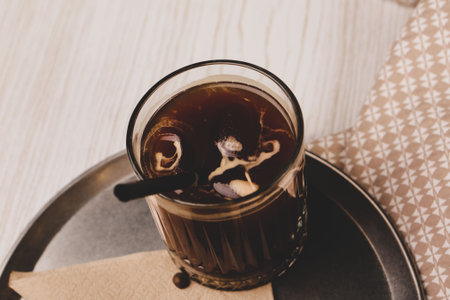 Iced coffee with milk. Iced coffee latte. Woman holding glass cup of iced coffee.