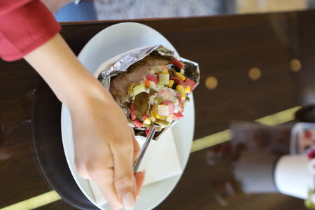 Baked kumpir potato stuffed with the cheese, sausage, olives, peppers and cornの写真素材