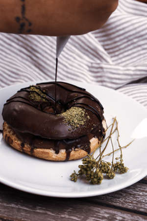 Delicious donut with chocolate sauce and pistachio nut pieces.の写真素材