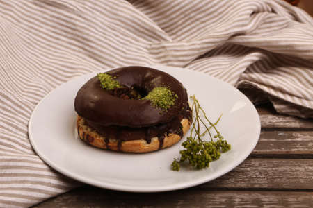 Delicious donut with chocolate sauce and pistachio nut pieces.の写真素材
