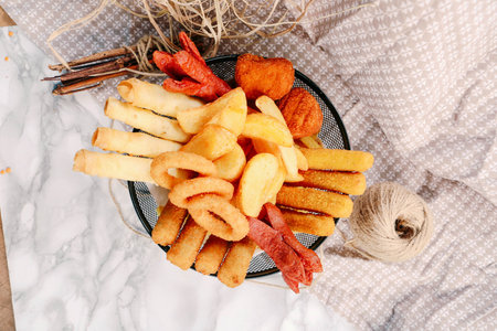 Delicious snack plate, french fries, onion rings, spring rolls or sausages on the table