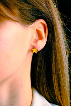 Close up of a woman's ear with a yellow star earring