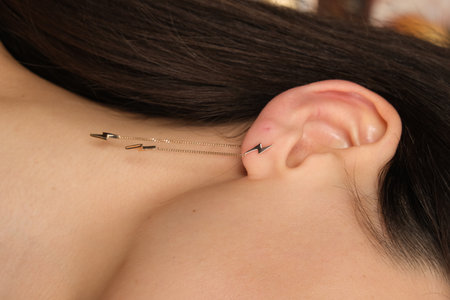 Minimalist gold chain with arrow-shaped pendants, worn as an ear cuff.の写真素材