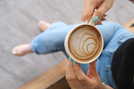 Cup of coffee with latte art in female hands, closeupの写真素材