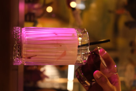 Hand holding a glass of cocktail on the background of the night club