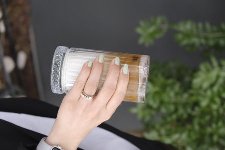 Female hand with beautiful manicure holding cup of cappuccinoの写真素材
