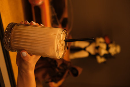 Female hand holding a glass of beverage on a dark backgroundの写真素材