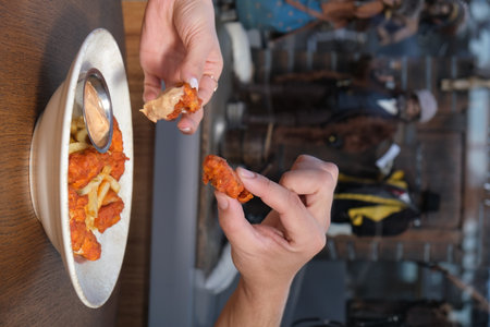 partial view of woman eating french fries and chicken nuggets in cafeの写真素材