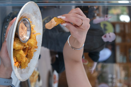 Woman eating deep fried chicken nuggets in a restaurant. Close-upの写真素材