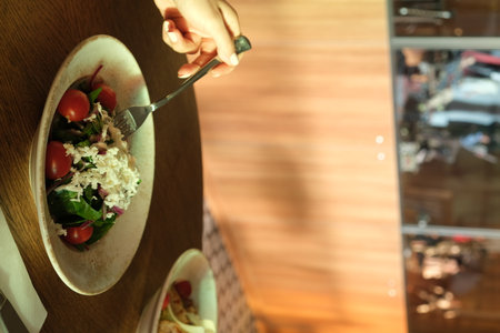 Woman eating healthy food in a restaurant. Close-up of a female hand holding a fork with a saladの写真素材