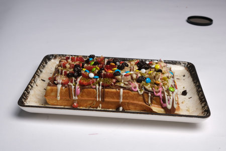 Belgian waffle topped with whipped cream, chocolate and sprinkles
