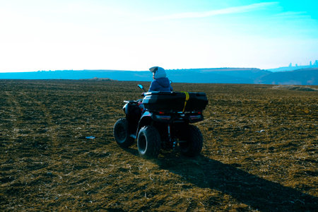 Silhouette of a man riding a quad bike in the field