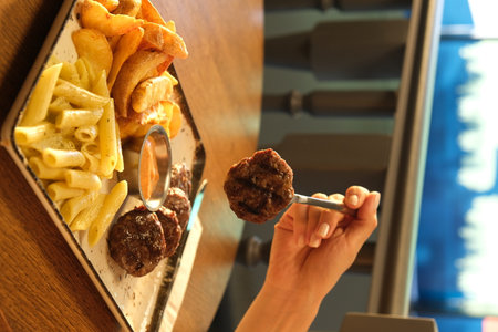 Woman eating hamburger in fast food restaurant, closeup of handsの写真素材