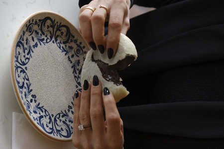 Person with black manicure holding a plate with chocolate cakeの写真素材