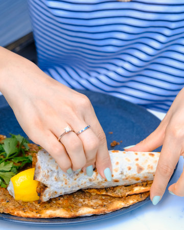 Woman hands with blue manicure holding a piece of pita breadの写真素材