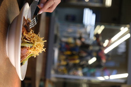 Woman eating hamburger in cafe, closeup. Food delivery serviceの写真素材