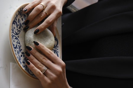 Female hands with black manicure and white nail design plate.の写真素材