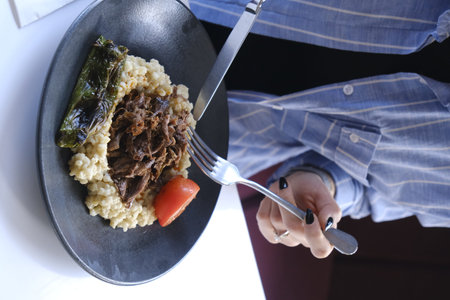 Rice with meat and vegetables in a black plate on the table