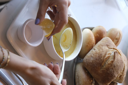 Woman eating fresh bread in the kitchen at home.の写真素材