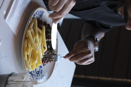 Man eating french fries in a restaurant, close-up of handsの写真素材