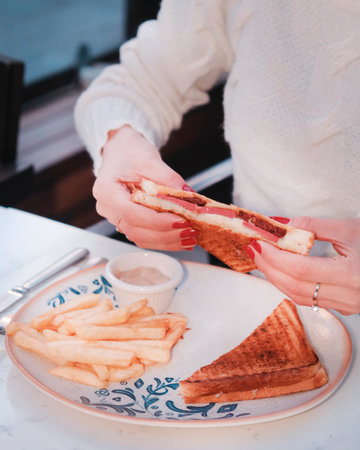 Woman eating sandwich in cafe. Close up of hands with french fries.の写真素材