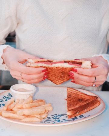 Woman eating sandwich with french fries in a cafe