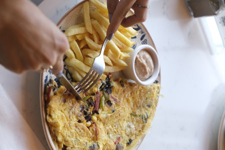 Woman eating omelette with fries, close up view.の写真素材