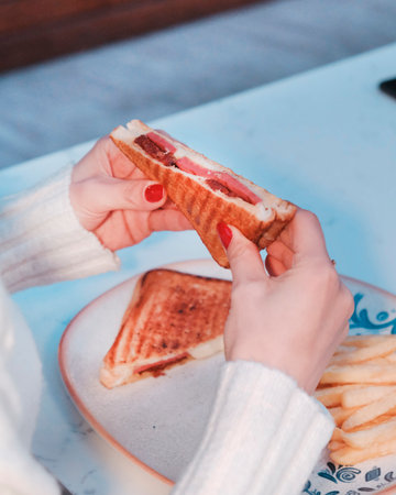 Woman's hand holding a sandwich on a blue plateの写真素材