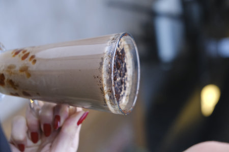 A woman is holding a glass of milkshake with chocolate.
