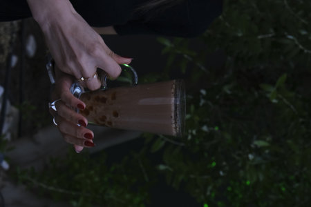 Close-up of a woman's hand holding a glass of coffeeの写真素材
