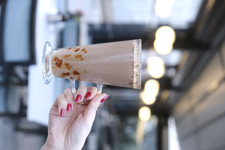 Woman holding glass of tasty milkshake on blurred background, closeupの写真素材