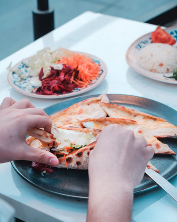 Hands of a man taking a piece of pizza from a plate