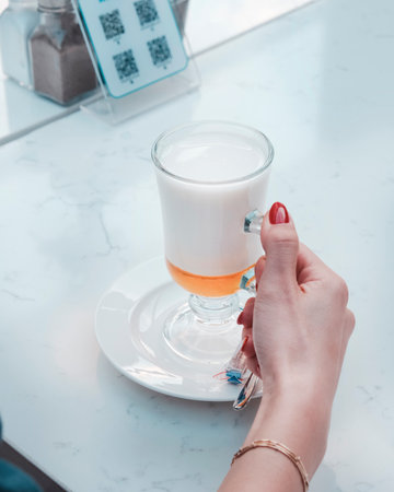 Female hand with red nail polish holding a glass cupの写真素材