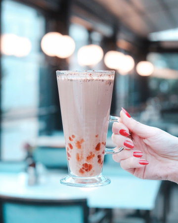 Woman hand holding a glass of chocolate milkshake in a cafe