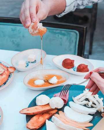 Rich and delicious breakfast. Hands of a woman pouring honey on bread.
