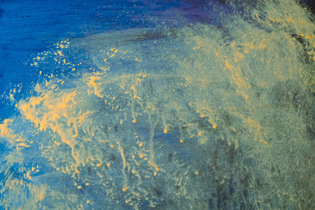 abstract background: yellow and blue paint on a blue sheet of paper