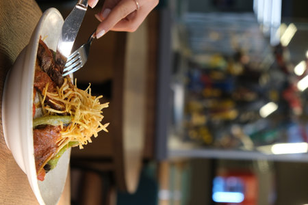 Woman eating steak with french fries in fast food restaurant, closeupの写真素材