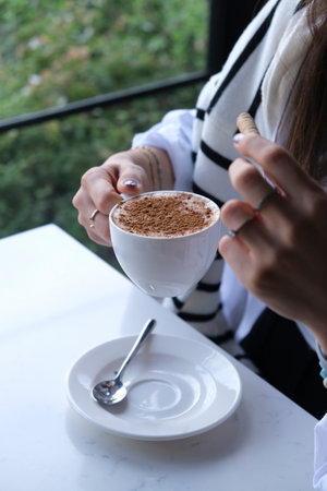 Close-up of female hands holding a cup of hot chocolate.の写真素材
