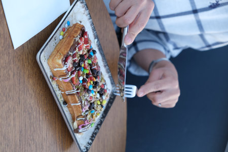 Close up of a woman eating a cake with whipped cream and fruitsの写真素材