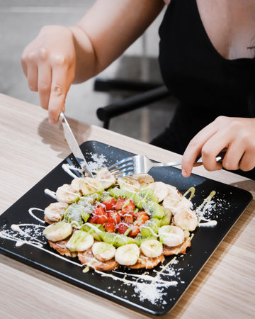 Woman eating salad with kiwi, cherry tomatoesの写真素材