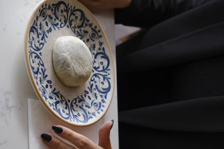 Bread dough on a plate in the hands of a woman.の写真素材