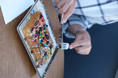 Woman eating waffle with whipped cream and chocolate topping in cafe.の写真素材