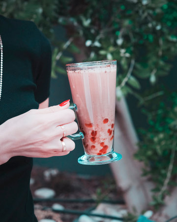 Woman's hands holding a glass of strawberry milkshake. Close-upの写真素材