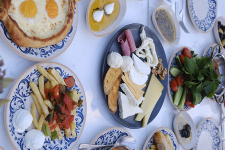 Breakfast table with fried eggs, ham, cheese, fruits and vegetablesの写真素材