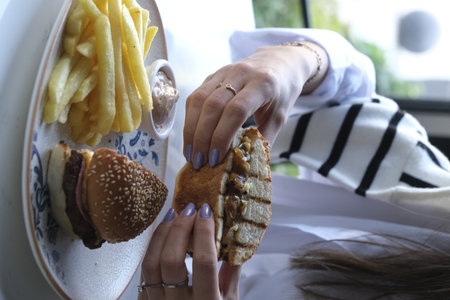 Woman eating hamburger and french fries.の写真素材